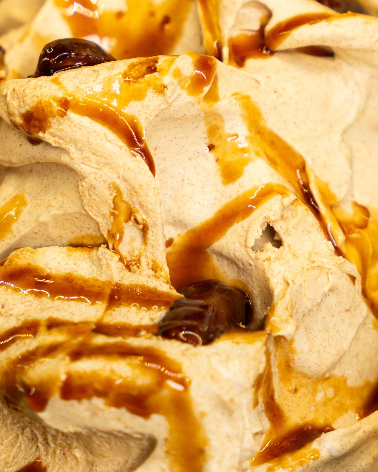 A close-up of caramel gelato swirled with ribbons of dark caramel sauce