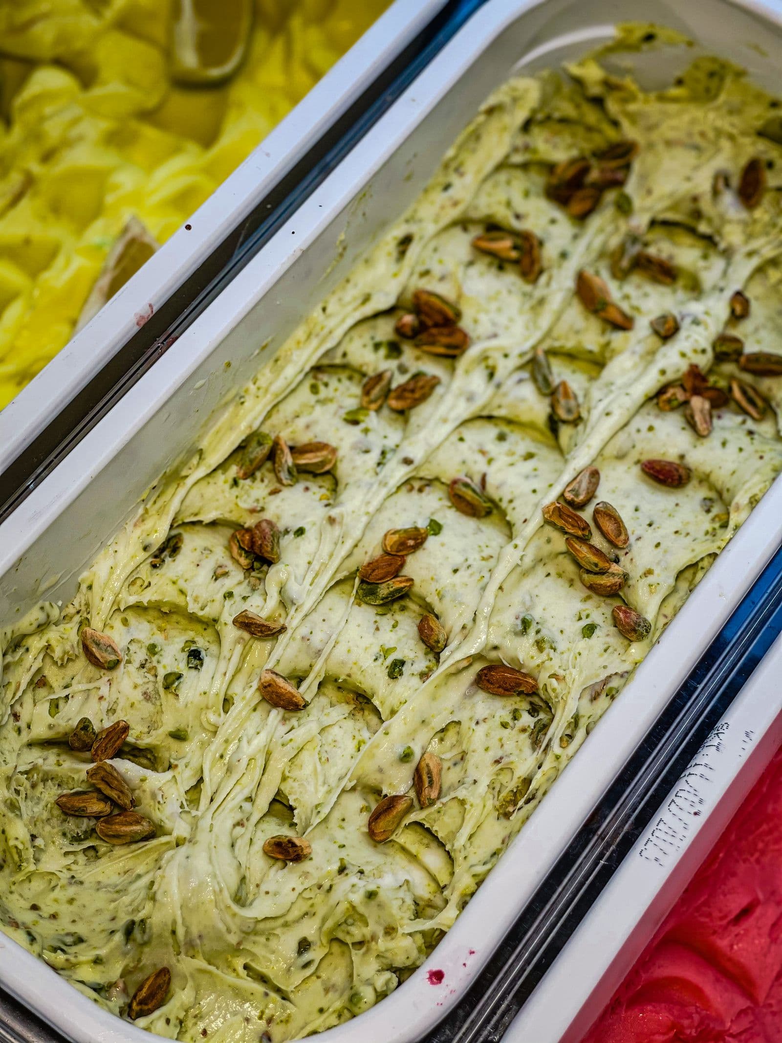 A tray of pale green pistachio gelato scattered with whole roasted pistachios